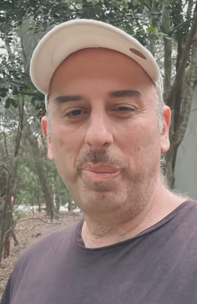 Close-up of man with beige cap and black T-shirt outdoors, enjoying nature in Mauritius. Perfect for lifestyle and outdoor apparel ads.