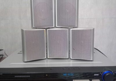 Wireless speaker system with five silver speakers and a black control unit.