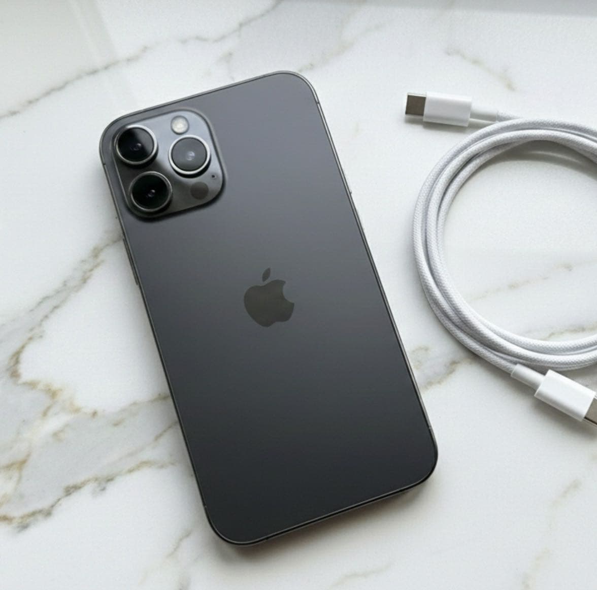 Apple iPhone 13 Pro Max in Graphite color with triple camera system and USB-C charging cable.