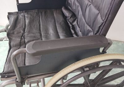 Wheelchair with black cushioned seat and backrest, metal frame, and large rear wheels. Suitable for mobility assistance and medical use.
