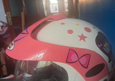 Helmet with pink and white design, cartoon character, and star accents.