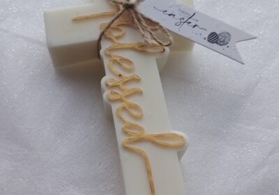White scented candle with “love” written in gold cursive, tied with a twine bow and a small tag.