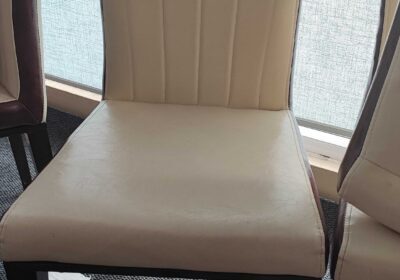 Modern beige upholstered dining chair with black wooden legs, ideal for home or restaurant use.