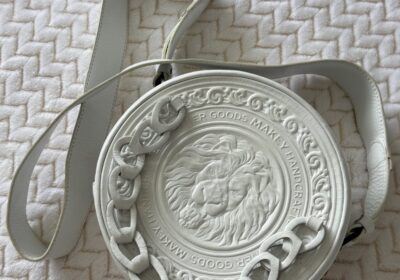 Wireless headphone with a circular design, white color, and lion emblem in the center, featuring a chain detail around the edge.