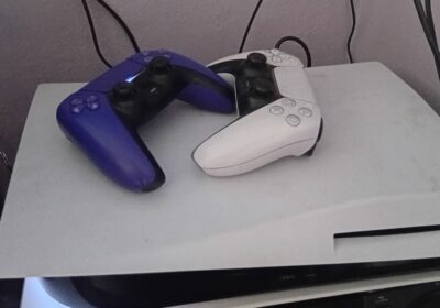 Game controllers for PlayStation, black and white, on a white console.