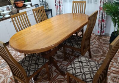 Wooden dining table with six matching chairs in a bright, cozy dining room.