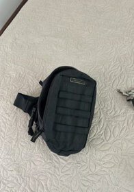Compact black tactical waist bag for outdoor activities and travel. Durable, lightweight, with multiple compartments for essentials.