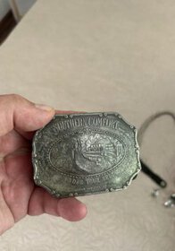 Vintage metal belt buckle with engraved Southern Comfort logo, silver color, rectangular shape with rounded edges.