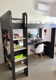 Compact black and white loft bed with storage shelves, children’s toys, and a study area, ideal for a kids’ bedroom in Mauritius.